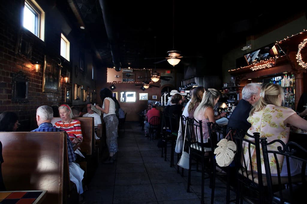 The dining room at Bacchus filled with warm light, brick walls, and guests in Richmond's Fan District